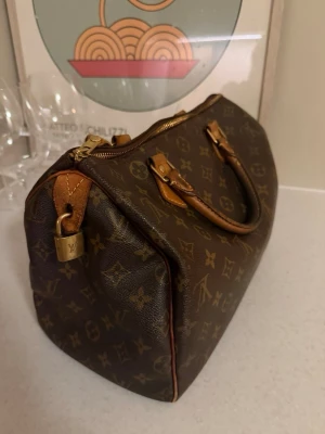 Louis Vuitton Speedy Monogram väska - Klassisk Louis Vuitton Speedy 30 handväska i brunt monogramcanvas med detaljer i läder och guldfärgade metalldelar. Ikoniskt LV-mönster över hela väskan och tidlös boxig form. Bra skick! Du hittar date code på tredje bilden 🌟🩷 