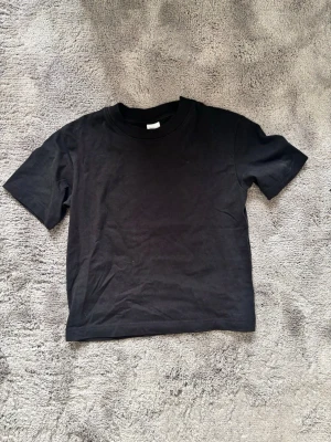 Svart finare basic t-shirt i bomull - En finare T-shirt från ginas basic kollektion. Säljer pågrund av att den bara lägger i min garderob. Aldrig använd. 