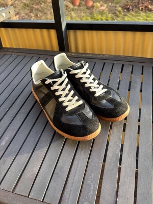 Svarta sneakers med mockadetaljer - Snygga svarta Margielas storlek 44. Är i ett topp skick, inga slitningar på sulan. Priset är inte hugget i sten. 1 av 1