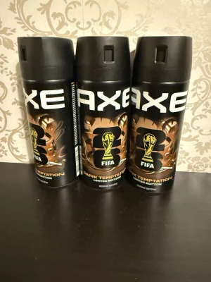 Axe Dark Temptation FIFA Limited Edition - Tre flaskor Axe Dark Temptation Limited Edition FIFA edition deodorant bodyspray. Svarta flaskor med guld- och bronsfärgade detaljer samt FIFA-logga. Modern och sportig design, perfekt för dig som gillar exklusiva samarbeten.