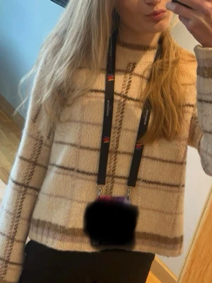 Beige rutig stickad tröja Mos Mosh - Säljer en stickad tröja från Mos Mosh i beige med brunt och rosa/lila rutmönster. Tröjan är i bra skick men är lite nopprig (jag tar bort det innan jag skickar tröjan) 