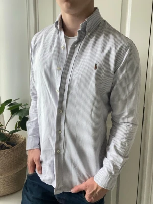 Ralph lauren skjorta  - Ralph lauren randig skjorta - lila vit . Inga defekter förutom minimala deo stains i armhålorna - märks inte ! Modellen i bilderna är 180 cm 75 kg och bär Storlek M  - rekommenderar inte för mindre , Kom med frågor! 🌟 (Kan gå ned i pris vid köp av paket 😉) 