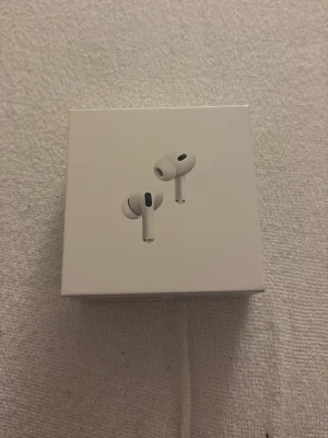Apple AirPods Pro in-ear hörlurar - Säljer ett par Apple AirPods Pro in-ear hörlurar i vit färg. De har en stilren och kompakt design med silikonpluppar och är tillverkade i plast. Perfekt för dig som vill ha trådlösa hörlurar med bra ljud och smidig anslutning till din iPhone.
