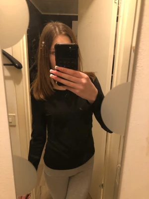 Svart långärmad topp - En enkel och stilren svart långärmad topp med rund hals. Passformen är slim och materialet känns mjukt och stretchigt, perfekt att matcha med olika outfits. Inga synliga detaljer eller mönster för en clean look.