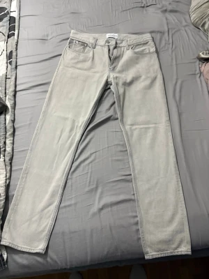 Ljusgrå raka jeans från Calvin Klein - Säljer ett par ljusgrå jeans från Calvin Klein med rak passform och klassisk femficksdesign. Jeansen har normal midja och är tillverkade i ett mjukt denimtyg. Perfekta för en clean och stilren look.