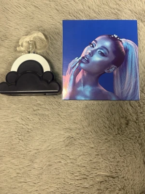 Ariana Grande Cloud parfym - Unik parfym från Ariana Grande i en cool flaska formad som ett moln. Flaskan är svart och vit med genomskinlig spraydel och har en modern, lekfull design. Kommer med originalkartong med färgstarkt motiv. Perfekt för dig som gillar trendiga dofter och snygga flaskor.