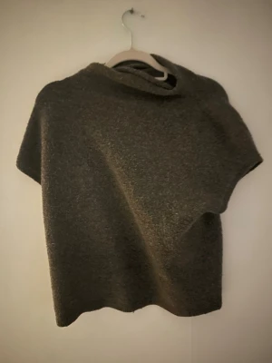 Mörkgrå stickad tröja - En enkel och stilren mörkgrå stickad poncho med korta ärmar och lös passform. Super mysigt och filt liknade material 