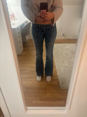 Blå bootcut jeans från Gina Tricot - Säljer ett par blå bootcut jeans från Gina Tricot. Jeansen har låg midja och klassisk femficksmodell. Perfekta för dig som gillar en avslappnad och trendig stil. Dem är använda ett par gånger men ser nya ut