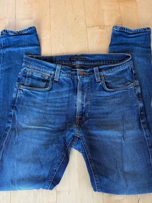 Blå jeans från Nudie Jeans - Säljer ett par klassiska blå jeans från Nudie Jeans.  Jeansen har en snygg tvätt och slimfit passform. Perfekta till vardagslooken och till dig som gillar stilrena detaljer. Modellen är Lean Dean. W30/L32