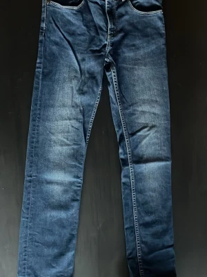 Mörkblå slim fit jeans från BOSS - Snygga mörkblå unika slim fit jeans från BOSS Hugo Boss i storlek 12 år men långa. Klassisk femficksmodell med raka ben och diskreta slitningar. Perfekta för dig som gillar en stilren och modern look. Jeansen är tillverkade i ett mjukt och stretchigt denimtyg. 