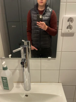 Mörkblå glansig väst från John Henric - Snygg svart dunväst med quiltad design och hög krage. Västen har dragkedja framtill och två praktiska fickor på sidorna som är magnetiska. Perfekt att slänga över en hoodie eller tröja för extra värme. Enkel och stilren look som passar till det mesta. Använd i en säsong säljer på grund  av för liten Nypris 1200 mitt pris 800 