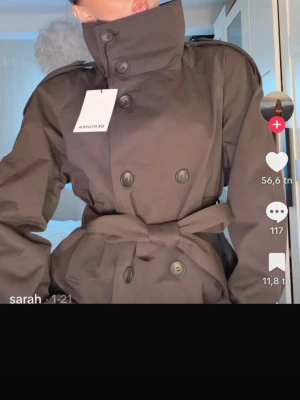 Brun trenchcoat från Bershka - Snygg brun trenchcoat från Bershka med dubbelknäppning, hög krage och bälte i midjan. Helt ny med prislapp i stlk xs, helt slutsåld på hemsidan 