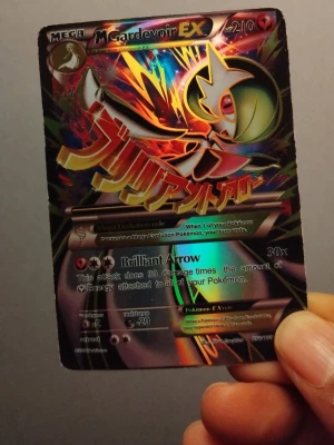 Pokémonkort Mega Gardevoir EX - Säljer ett M Gardevoir EX Pokémonkort med holografisk yta och färgstark design. Kortet har coola effekter och attacker som Brilliant Arrow. Perfekt för samlare eller dig som vill boosta din lek med en mäktig Mega Evolution.