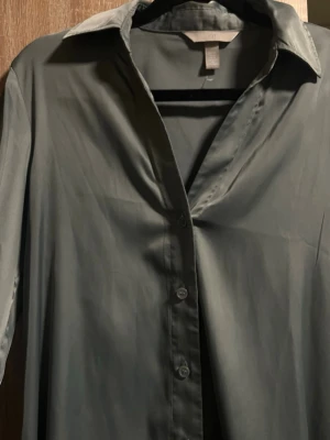 En jätte fin silkesskjorta , från H&M  - Kommer inte till användning men jätte fin skjorta , storlek  S/xs , jätte fin färg nu till sommaren  ( grön blå ) 