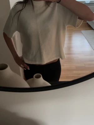 Vit fin stickad tröja 💞 - Säljer en vit croppad stickad tröja med korta ärmar och hög hals. Tröjan har en avslappnad passform och är perfekt för lager-på-lager. Enkel och stilren design som passar till det mesta 💞