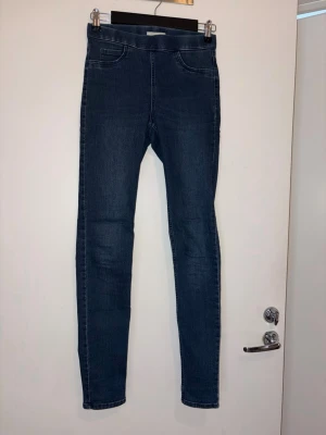 Mörkblå skinny jeans från H&M - Snygga mörkblå skinny jeans från H&M i storlek 34. Jeansen har klassisk femficksdesign, hög midja och smal passform hela vägen ner. Perfekta till vardagslooken och lätta att matcha med olika stilar. Materialet är stretchigt för extra komfort.