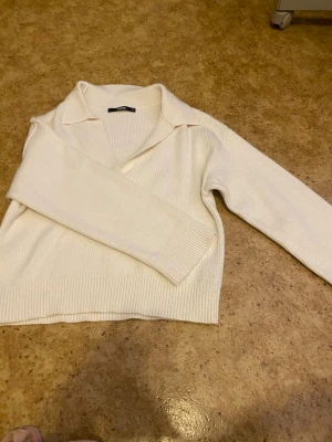 Vit stickad tröja med krage BikBok - Säljer en vit stickad tröja från BikBok i storlek XS. Tröjan har en snygg krage och v-ringning, samt ribbstickat material som ger en stilren look. Perfekt för lager-på-lager och passar till många outfits. Inte använts så mycket alls.