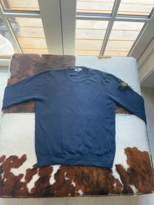 Mörkblå stickad tröja Stone Island - Snygg mörkblå stickad tröja från Stone Island med klassisk rund halsringning och ikonisk logotyp-patch på vänster ärm. Tröjan har ribbade muddar och är tillverkad i ett mjukt, stickat material som passar perfekt till lager-på-lager-stil. (Passform: jag är 190 lång och väger 80kg, sitter tight på mig)