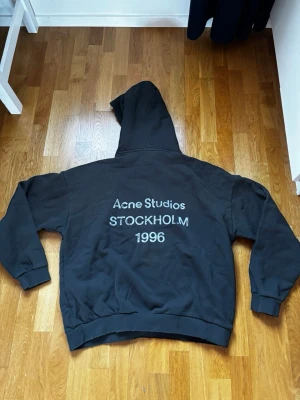 Acne Studios Stockholm - Svart hoodie från Acne Studios med stor huva och tryck på ryggen där det står 'Acne Studios STOCKHOLM 1996'. Oversized passform och ribbade muddar. Perfekt för en chill och trendig look. Pris går att diskutera vid snabb affär!!