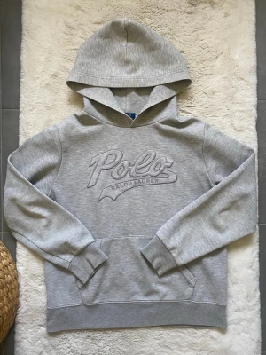 Grå hoodie från  Ralph Lauren - Snygg grå ralph lauren hoodie i mycket bra skick förutom de små vita missfärningarna under luvan som inte syns när man har på sig den (se bild) Strolek xs.