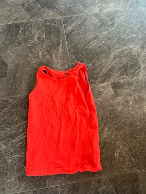 Röd ärmlös linnetopp från H&M - Snygg röd linnetopp från H&M med enkel och stilren design. Toppen är ärmlös och har en rund halsringning, perfekt för varma dagar eller som lager under en skjorta. (Plus frakt) 