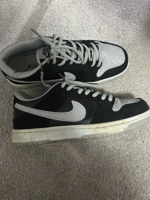 Nike SB Dunk Low svart/vit - Säljer ett par Nike SB Dunk Low sneakers i svart och vitt.  Storlek 37, använd 2 gånger. Behöver endast rengöras lite men annars i fint skick 