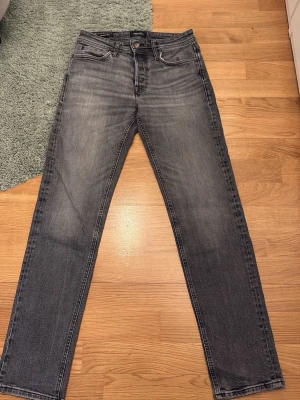 Grå straight fit jeans från Jack and Jones  - Säljer ett par gråa tapered/ Mike  jeans från Jack and Jones med klassisk femficksdesign. Perfekt för dig som gillar en avslappnad och tidlös look. Hör av er vid frågor!👍