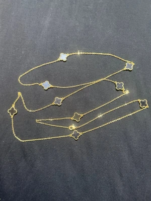 Guldhalsband med svarta klöverhängen - Snyggt halsband i guld med flera svarta klöverformade hängen längs kedjan. Kedjan är tunn och elegant, och klöverhänget ger en lyxig och trendig känsla. Perfekt accessoar för att lyfta din outfit.