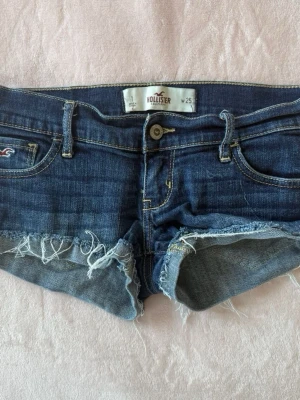 Mörkblå jeansshorts från Hollister - Snygga mörkblå jeansshorts från Hollister låg midjade !! FÖRSTA 2 BILDERN ÄR INTE MINA  !! Lyckades inte få bra bilder så tog dessa men de är samma endast mörkare än första bilden och storlek W26 och inte W25
