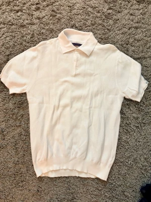 Vit pikétröja från Regatta - Klassisk vit pikétröja från Regatta med korta ärmar och krage. Tröjan har tre knappar framtill och är tillverkad i ett mjukt bomullsmaterial. Perfekt till jeans eller shorts för en clean och enkel stil.