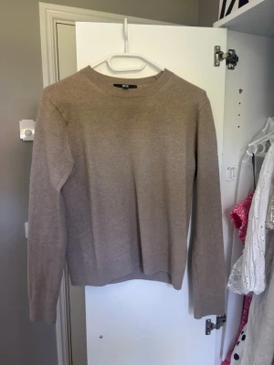 Beige stickad tröja från Uniqlo - Säljer en stilren beige stickad tröja från Uniqlo. Tröjan har rund halsringning, långa ärmar och ribbade muddar vid ärmslut och nederkant. Perfekt basplagg i mjukt material som passar till det mesta. 100% chasmir