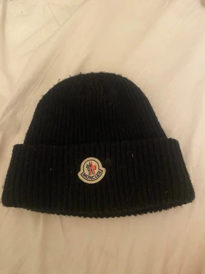 Svart mössa från Moncler - Säljer en svart mössa från Moncler.Använd bara en gång. Kvittot finns tyvärr inte den hittades inte.