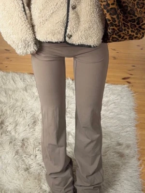 Beige utsvängda leggings - Snygga beige leggings med utsvängda ben och hög midja. Stretchigt och mjukt material som sitter skönt på kroppen. Perfekta för en trendig och avslappnad look.