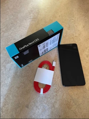 OnePlus Nord CE5 8GB/128GB Black - OnePlus Nord CE5 Android-telefon i färgen Black Infinity med 8GB RAM och 128GB lagring. Telefonen har en stilren svart design, stor skärm och levereras med originalkartong och röd USB-C laddkabel. Drivs av MediaTek Dimensity-processor.