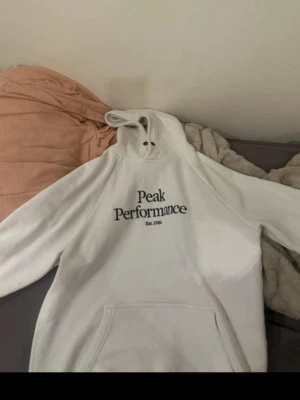 Vit hoodie Peak Performance - Säljer en vit Peak Performance hoodie i storlek M, men den passar även L beroende på önskad passform.  Skicket är bra överlag. Hoodien har några väldigt små hål framtill och ett litet hål baktill, men de är knappt synliga och påverkar varken funktionen eller hur den ser ut när den används (se bilder).  ✅ Storlek: M (passar även L) ✅ Färg: Vit ✅ Mjuk och bekväm  Skicka gärna meddelande om du har frågor!  ⸻  🇬🇧 English  Peak Performance Hoodie – White – Size M (Fits L as well)  Selling a white Peak