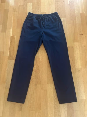 Les Deux kostymbyxa drawstring - Säljer nu mina marinblåa drawstring kostymbyxor från Les Deux. Byxorna är i väldigt bra skick. Storlek: M. Passform: Regular fit. Mått: midja 39cm, längd 107cm.