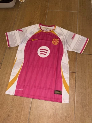 Barcelona matchtröja rosa nike - Säljer en Barcelona matchtröja i rosa, vitt och gult med tryckta loggor från Nike, Spotify och UNHCR. Tröjan har korta ärmar, rund hals och namn/nummer Lamine Yamal 10 på ryggen. Storlek M 