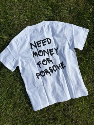 Need money for Porsche Vit t-shirt med tryck - Vit t-shirt med svart text på ryggen där det står 'NEED MONEY FOR PORSCHE' i en lekfull font. Klassisk passform och rund hals. Perfekt för dig som gillar statement-plagg och vill sticka ut. 100% bomull bra kvalitet 