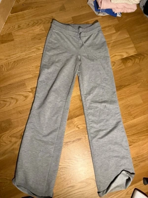 Grå mjukisbyxor med raka ben - Grå mjukisbyxor med raka ben och dragsko i midjan. Byxorna har en enkel och avslappnad design, perfekta för en chill stil. Tillverkade i mjukt och bekvämt material som känns skönt mot huden.