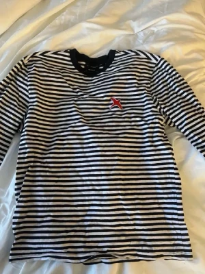Randig långärmad tröja - Säljer en svartvit randig långärmad topp från Axel Arigato med den broderade röda fågel loggan på bröstet. Den är perfekt nu när randigt blivit trendigt igen! Storlek: M. Priset kan diskuteras!