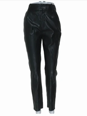 Svarta byxor i skinnimitation - Snygga svarta byxor i skinnimitation med hög midja och avsmalnande ben. Byxorna har bälteshällor och stängs med knapp och dragkedja. Perfekta för en trendig och edgy look.