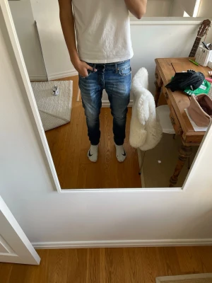 Blå slim fit jeans med slitningar - Säljer ett par blå  jeans med snygga slitningar och tvättade detaljer. Har aldrig använd de och de passar perfekt att ha året om. Storlek 32/32