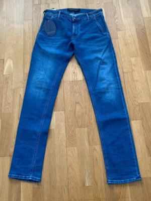Blå raka jeans med klassisk passform - Säljer ett par blå jeans med rak passform och normal midja. Jeansen har fem fickor, bälteshällor och snygga slitningar framtill för en avslappnad look. Materialet är klassisk denim i bomull. Perfekta till en casual outfit.