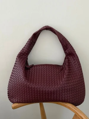 Vinröd/burgundy populär flätad lite större väska  - Tyvärr kommer inte min snygga design by si väska till användning. En vinröd/burgundy flätad väska, perfekt som skolväska eller som shoppingväska. Större än ett a4🌸  Superfint skick! Använd fåtal tillfällen. nypris 600:-