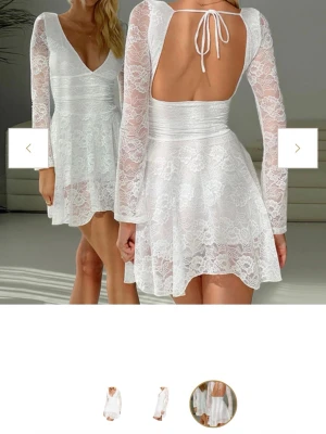 Vit spetsklänning med öppen rygg - Kort vit klänning från dressy, i spets med v-ringning från, långärmad design och öppen rygg med knytband. Stl S aldrig använd då den var lite liten på mig så skulle säga att den är som en xs i storleken.