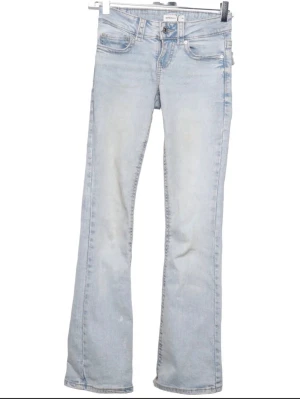 Ljusblå bootcut jeans från Gina Tricot - ljusblå bootcut jeans från Gina tricot. De har klassisk femficksdesign, snygga detaljer på bakfickorna med knappar och en bekväm midja. Jeansen är i mjukt denimtyg och har en lätt utsvängd passform nedtill.