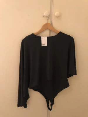 Stringbody med capedetalj - Stringbody med capedetalj, helt ny, liten i storleken 