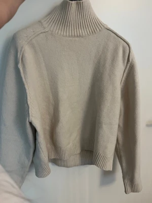 Beige polotröja i stickat material - Säljer en beige stickad polotröja med halvkrage från HM.