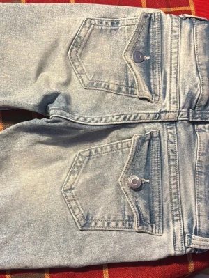Ljusblå bootcut jeans med ficklock - Säljer ett par ljusblå bootcut jeans med två stora fickor bak som har ficklock och silverfärgade knappar. Finns inte kvar på hemsidan/slutsåld? 🩷