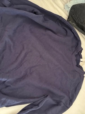 Mörkblå oversized sweatshirt - En enkel och stilren mörkblå sweatshirt med rund hals och avslappnad passform. Perfekt för en chill vardagslook och lätt att matcha med jeans eller leggings. Mjuk bomullskänsla och långa ärmar.